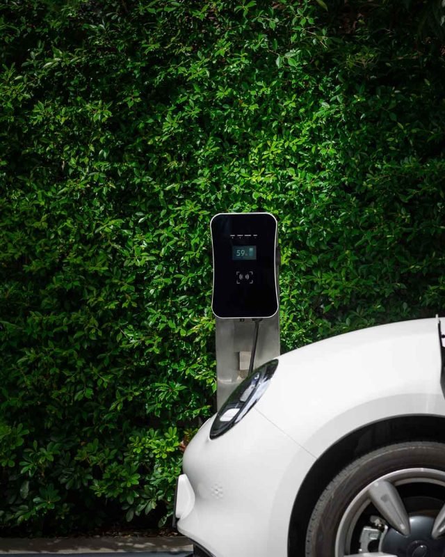 side-view-progressive-ev-car-with-charging-station-green-foliage-background