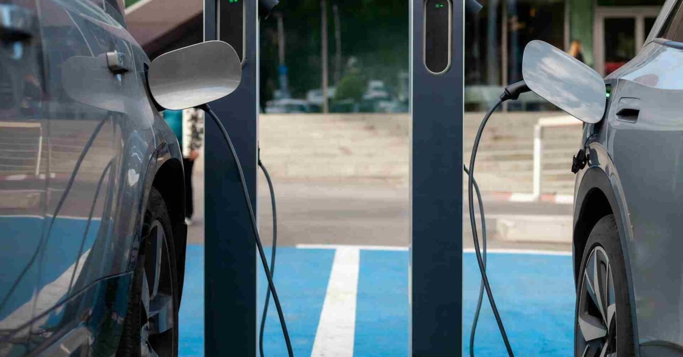 Saudi Lithium Energy Hub: Two electric vehicles are plugged into charging stations in a modern parking area, with visible charging cables and a green connection light.