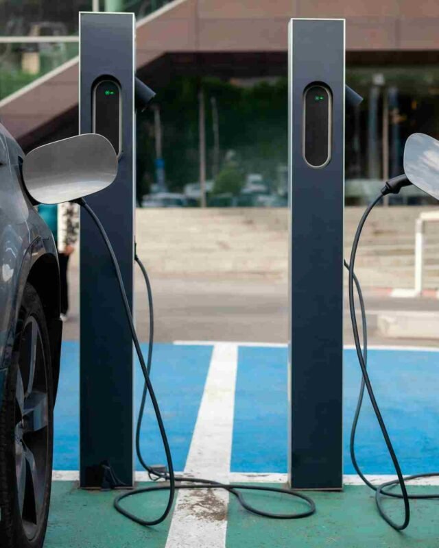 Saudi Lithium Energy Hub: Two electric vehicles are plugged into charging stations in a modern parking area, with visible charging cables and a green connection light.