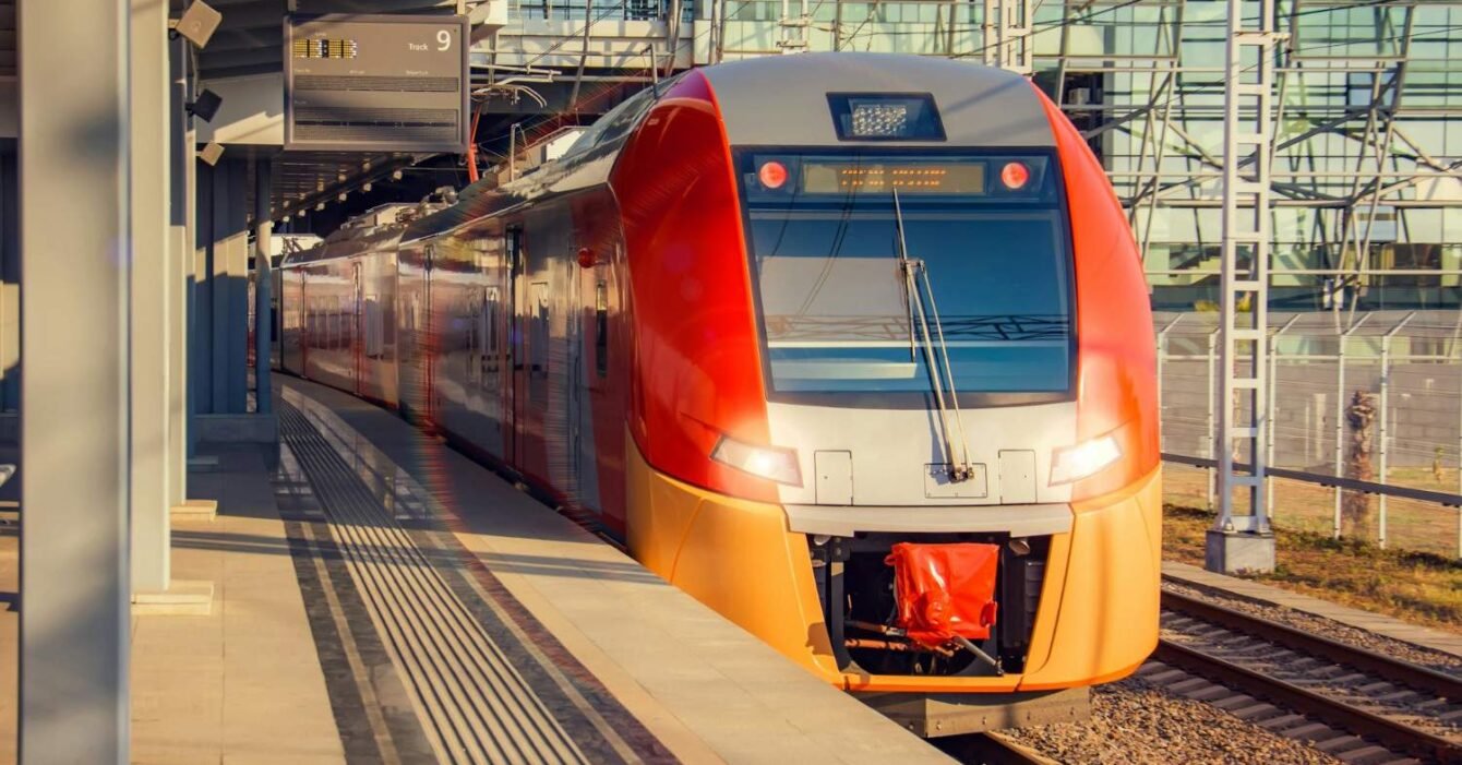 Micromobility in Saudi Arabia: A modern, streamlined train with a red front is parked at a station under an overhead sign indicating Track 9.